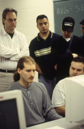 Photograph of students gathered around the computers in the lab
