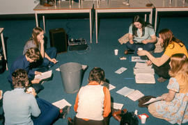 Photograph of students sitting on the floor in a classroom listening to tape recorder