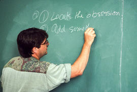 Photograph of Paul Quarrington writing on a chalkboard
