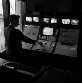 Photograph of a TV producer adjusting camera monitors in the control room