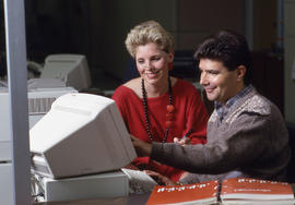 Photograph of two people seated infront of a computer