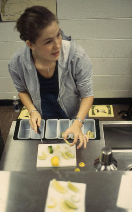 A photograph of a Bartending student slicing lemons and limes