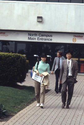 Photograph of people walking from the main college entrance