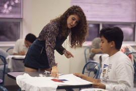 Photograph of a Student Working on Painted T-Shirt Designs