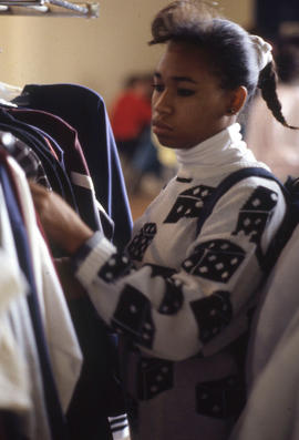 Photograph of an unknown person looking through clothing items
