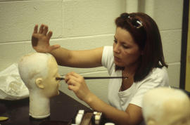 A photograph of a Funeral Services student applying makeup on her mannequin
