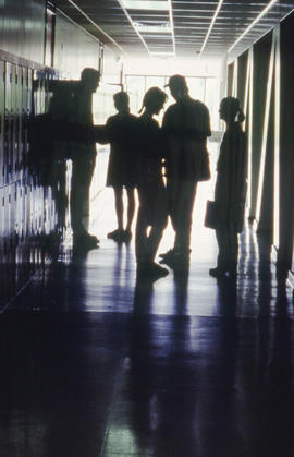 Photograph of students standing in silhouette in a hallway of building "E"