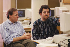 Photograph of George Byrnes sitting at a computer with a student