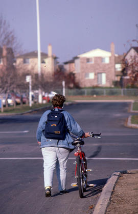Photograph of a person walking with their bicycle