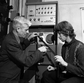 Photograph of Art Penny working with a student on an early form of numerical control equipment us...
