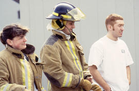 A photograph of three students, two of them in firefighting gear
