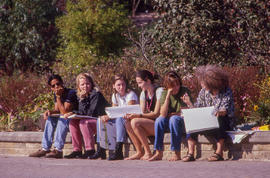 Photograph of a group of people sitting on a wall