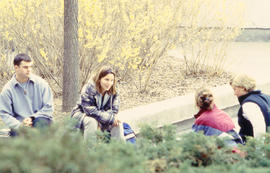 Photograph of students sitting on a curb and engaged in conversation
