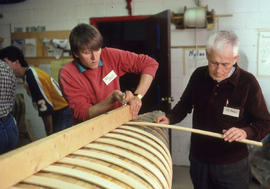 Photograph of Instructor directing a student in the construction of a canoe