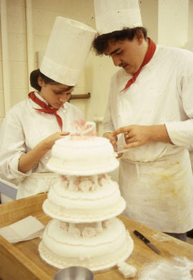 Photograph of Hospitality students decorating a three-tiered wedding cake