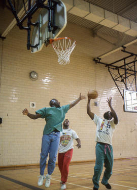 Photograph of three students playing a friendly game of basketball