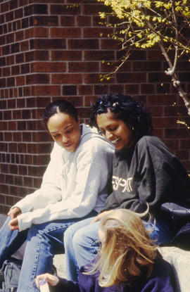 A photograph of three students sitting outside