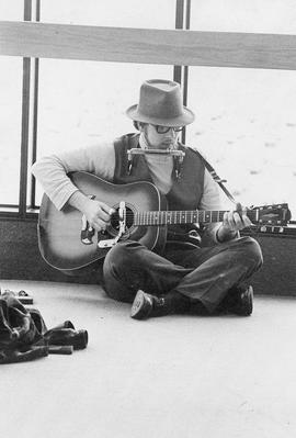 Photograph of Mike Thompson Playing his Harmonica and Guitar
