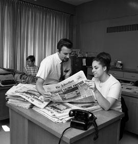 Photograph of Walt McDayter and Sharon Airhart reading the newspaper