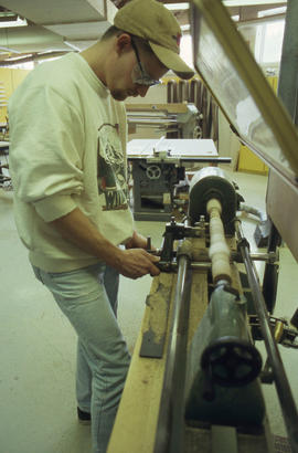A photograph of a student using a lathe in the woodworking lab