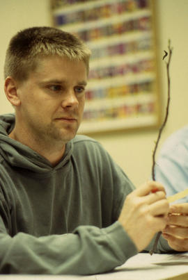 A photograph of a Floriculture student examining a twig
