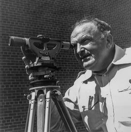 Photograph of Des Thompson Looking Through a Survey Lens