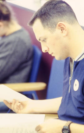 A photograph of a student looking down at their notes