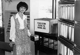 Photograph of Librarian Karina Fong Standing Beside Cataloging Drawers