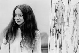 Photograpgh of a Nursing Student Standing Beside a Human Body Poster