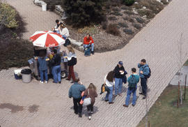 Photograph of People Standing Outside Talking by a Hot Dog Stand
