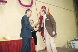 Photograph of Dr. Robert A "Squee" Gordon presenting an award at the President's Breakfast