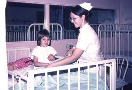 Photograph of a Humber Nursing student attending to a young girl in a pediatric ward at the hospital
