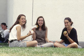 Photograph of Three Girls Eating a Hot Dog on the Grass