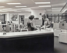 Photograph of a Faculty Member Receiving Help from a Librarian at the Reference Desk in the Library