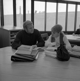 Photograph of two individuals sitting in the library study area