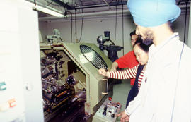 Photograph of students working in the Mechanical Engineering lab with a computerized numerical co...