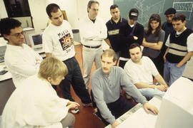 Photograph of students gathered around the computers in the lab