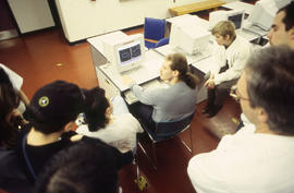 Photograph of students gathered around the computers in the lab