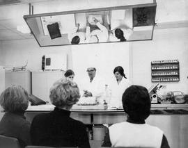 Photograph of Igor Sukor and Students Preparing a Roast in a Demonstration Kitchen Classroom