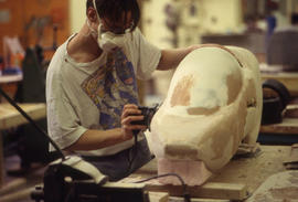 A photograph of an Industrial Design student sanding one of their designs
