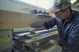 Photograph of a student using a piece of equipment in the woodworking lab to laminate pieces of w...