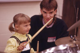 Photograph of a child with drum sticks in hand