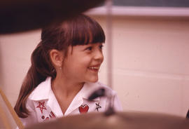 Photograph of child with drum sticks in hand