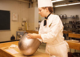 Photograph of a student in the Culinary program and an industrial mixing bowl