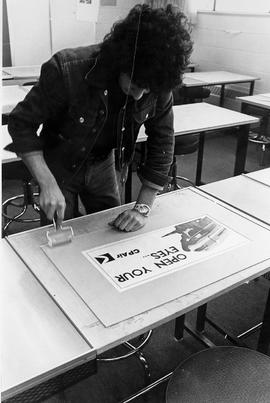Photograph of a Design Student Working on a Poster in a Lab
