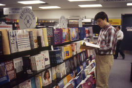 Photograph of an unknown person flipping through a book at the bookshop