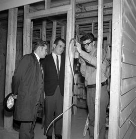 Photograph of visitors viewing a demonstration of residential electrical installation during an o...