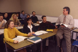 Photograph of Faculty member sitting on desk lecturing to students