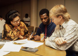 Photograph of three students putting their heads together during a math contest