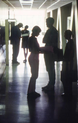 Photograph of students standing in silhouette in a hallway of building "E"